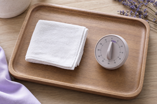 Folded white washcloth next to a kitchen timer near two minutes, symbolizing measured warm compress heat loss.